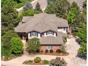 Aerial view of a two-story home featuring mature landscaping, a concrete driveway, and a complex roof line at 9880 E Progress Cir, Greenwood Village, CO 80111