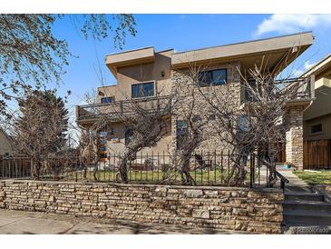 Contemporary two-story home featuring stone accents, a balcony, manicured landscaping, and gated front yard at 3323 W Hayward Pl, Denver, CO 80211