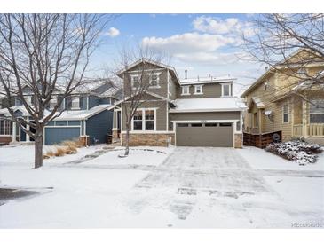 Two-story house with a large driveway, snow-covered lawn, and neutral color scheme at 10251 Rifle St, Commerce City, CO 80022