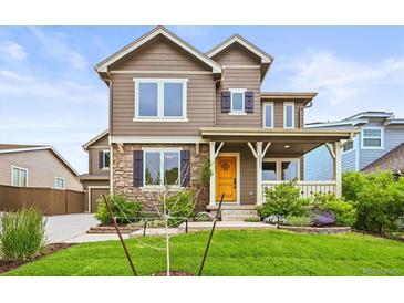 Charming two-story home with stone accents, a landscaped yard, and a welcoming front porch and yellow door at 10235 Rustic Redwood Ln, Highlands Ranch, CO 80126