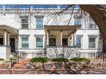 Charming two-story white brick home featuring a covered front porch and well-maintained landscaping at 325 E 7Th Ave, Denver, CO 80203