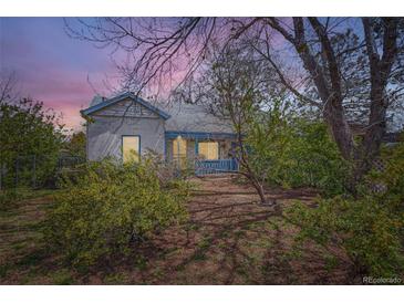 Charming single-story home with gray siding, blue trim, and mature trees under a colorful sky at 2022 S Clay St, Denver, CO 80219