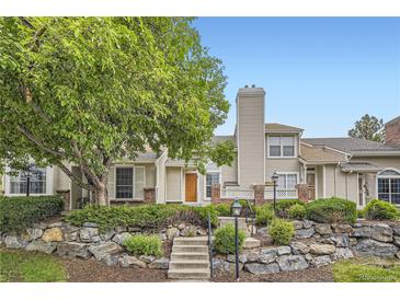 Charming home featuring stone accents, a well-manicured lawn, mature landscaping, and a welcoming front entrance at 2902 W Long Cir # B, Littleton, CO 80120