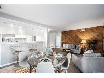 Inviting living space featuring wood accent wall, modern seating, and a stylish dining area with bar seating at 12470 E Cornell Ave # 104, Aurora, CO 80014