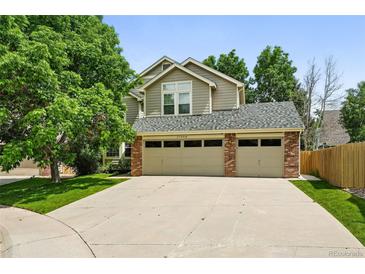 Charming two-story home showcasing a three-car garage and a beautifully landscaped front yard with mature trees at 17058 Hastings Ct, Parker, CO 80134