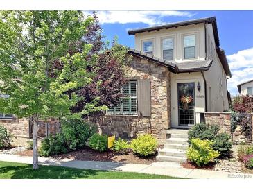 Charming two-story home featuring stone accents, a welcoming front porch, and beautiful landscaping at 15569 W La Salle Ave, Lakewood, CO 80228
