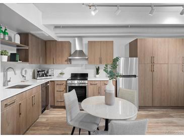 Well-lit kitchen featuring stainless steel appliances, light wood cabinetry, and an adjacent dining area at 1495 Vrain St # 214, Denver, CO 80204