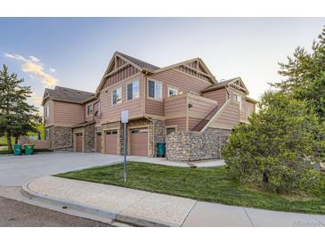 A well-maintained townhouse with tan and brown siding and stone accents and attached garages at 5757 S Algonquian Way # E, Aurora, CO 80016