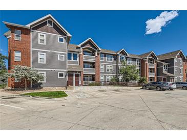 Apartment building featuring gray siding, brick accents, multiple floors, and a convenient parking area at 14251 E 1St Dr # 305, Aurora, CO 80011