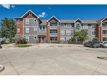 Three-story condo building with gray siding, brick accents, and convenient parking at 14251 E 1St Dr # 305, Aurora, CO 80011
