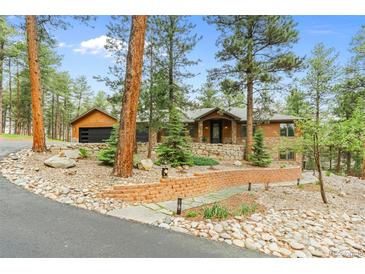 Stunning wood and stone home with rock landscaping and a brick retaining wall in a wooded area at 7597 Molas Ct, Larkspur, CO 80118