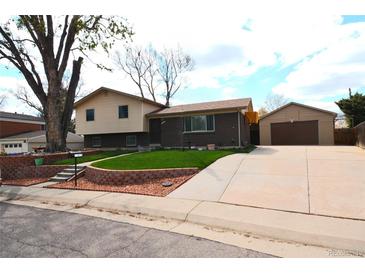 Charming two-story home with brick accents, a well-maintained lawn, and a detached garage with long driveway at 11823 Williams Way, Northglenn, CO 80233