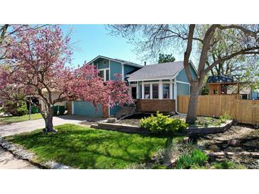 Charming exterior of a blue home showcasing a blossoming tree, green lawn, and well-maintained landscaping at 15962 E Lehigh Cir, Aurora, CO 80013