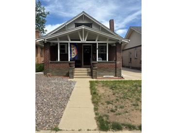 Charming brick home with a covered porch, walkway, and landscaping at 4536 Beach Ct, Denver, CO 80211