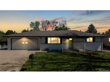 Charming home with lush lawn, attached garage, and lovely curb appeal at sunset at 6931 W 75Th Pl, Arvada, CO 80003