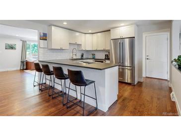 Bright kitchen featuring white cabinets, stainless steel appliances, and a breakfast bar with seating for four at 6931 W 75Th Pl, Arvada, CO 80003