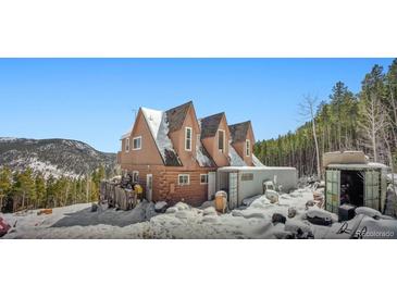 Charming three-story home showcasing its unique architecture and wintery surroundings at 6100 Bear Paw Rd, Golden, CO 80403