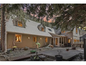 Charming home featuring a large wooden deck, gravel landscaping, and dormer windows under a dusk sky at 916 Griffith St, Georgetown, CO 80444