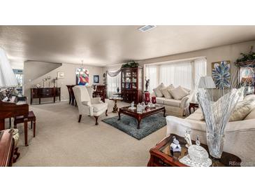Spacious living room features comfortable seating, elegant décor, and natural light from large windows at 9741 Chambers Dr, Commerce City, CO 80022