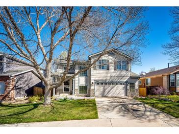 Charming two-story home with a well-manicured lawn, tree, and a two-car garage on a sunny day at 7083 Leopard Dr, Lone Tree, CO 80124