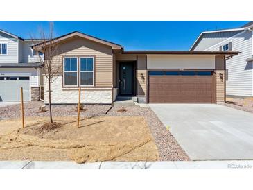 Charming single Gathering home with a beige stone and vinyl exterior and a two-car garage at 9141 Telluride Ct, Commerce City, CO 80022