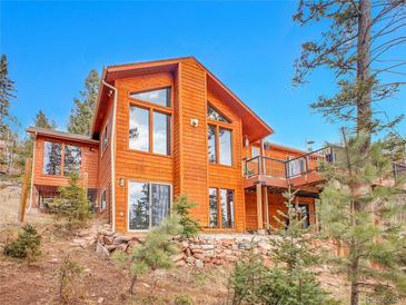 Stunning exterior view of a wood home featuring large windows and a deck with scenic views at 30813 Kings Valley Dr, Conifer, CO 80433