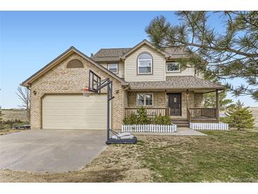 Charming two-story home with brick accents, front porch, and attached two-car garage with basketball hoop at 49950 Oak Park Dr, Bennett, CO 80102