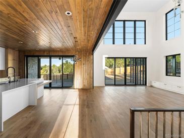 Bright, open living room features hardwood floors, wood paneled ceilings, and large windows with sliding doors to the outside at 5326 Lions Paw St, Castle Rock, CO 80104