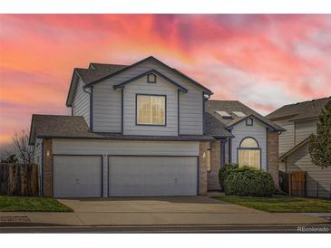 Two-story home featuring a three-car garage and sunset sky at 3823 S Uravan St, Aurora, CO 80013