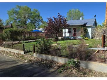 Charming single-story home with a well-manicured front yard, mature trees, and an inviting red front door at 4635 Teller St, Wheat Ridge, CO 80033