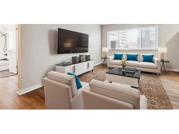 Bright living room features hardwood floors, comfy seating, and a large TV at 1101 Bellaire St # 108, Denver, CO 80220