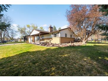 Spacious ranch-style home with a lush lawn, mature tree, and covered porch, perfect for outdoor living at 625 Ammons St, Lakewood, CO 80214
