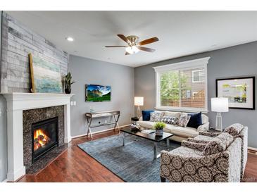 Cozy living room featuring a fireplace, modern ceiling fan, and comfortable seating area with natural light at 602 Mathews Way, Erie, CO 80516