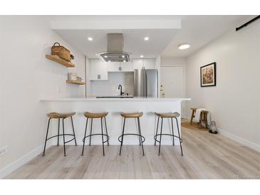 Modern kitchen featuring stainless steel appliances, white cabinetry, and stylish breakfast bar with seating at 955 Eudora St # 1606, Denver, CO 80220