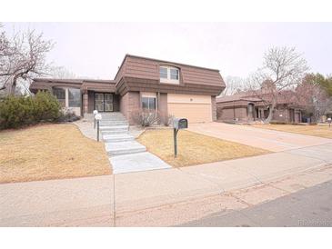 Charming brick home with a unique roof, tidy front yard, and attached two car garage at 3957 S Peach Way, Denver, CO 80237