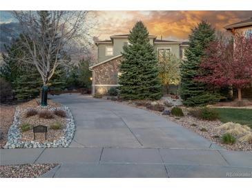 Inviting home with a long driveway, lush greenery, and beautiful stone accents at 20148 E Windy Pine Pl, Parker, CO 80134
