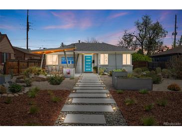 Charming gray brick home featuring a walkway to a bright blue front door and artistic modern landscaping at 822 Poplar St, Denver, CO 80220