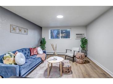 Cozy living room featuring a blue velvet sofa, stylish décor, and bright natural lighting at 3047 W 47Th Ave # 105, Denver, CO 80211