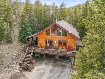 Stunning log home with expansive deck, nestled amongst the trees, and featuring an attached garage for convenience at 1673 Sinton Rd, Evergreen, CO 80439