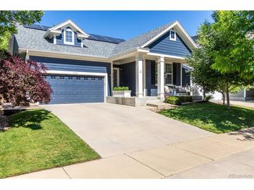Charming blue two-story home with landscaped yard, solar panels, and covered porch with seating at 1038 Mircos St, Erie, CO 80516