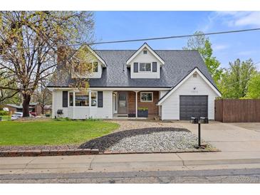 Charming two-story home featuring dormer windows, a manicured lawn, and a cozy covered front porch at 12212 W 60Th Pl, Arvada, CO 80004