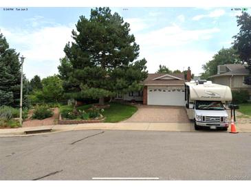 Ranch-style home with brick driveway, white garage door, landscaped yard, and an RV in front at 13126 W Warren Cir, Lakewood, CO 80228
