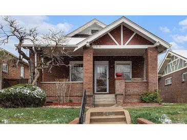 Charming brick home with a covered front porch and landscaped front yard with a dusting of snow at 3159 36Th Ave, Denver, CO 80211