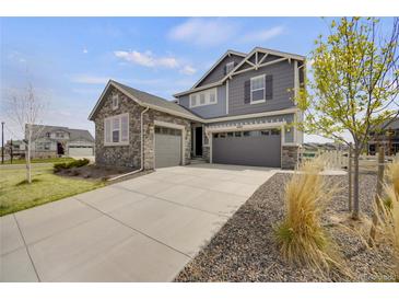 Attractive two-story home featuring a three-car garage and a blend of stone and gray siding at 6802 S Uriah St, Aurora, CO 80016
