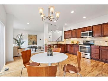 Bright kitchen featuring wood cabinets, granite counters, stainless appliances, and hardwood floors at 4190 W Alameda Ave, Denver, CO 80219