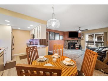 Inviting dining area with a stylish table set, opening to a cozy living space with a stone fireplace at 3482 S Eagle St # 102, Aurora, CO 80014