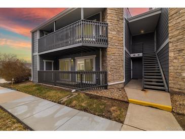 Stylish condo featuring stone accents, private balconies, and gray siding under a vibrant sunset sky at 3482 S Eagle St # 102, Aurora, CO 80014