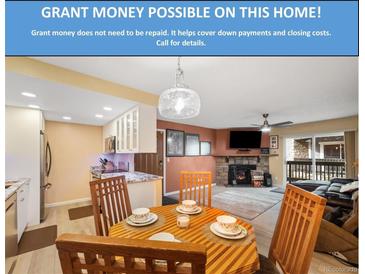 Cozy living room featuring a fireplace, dining area, and access to the outdoors at 3482 S Eagle St # 102, Aurora, CO 80014