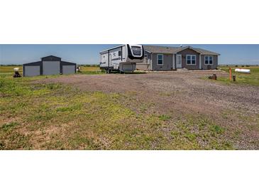 Gravel driveway leads to a charming single-story home with a detached garage and parked RV at 11809 Pass Me By Rd, Strasburg, CO 80136