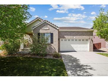Charming brick home boasts a well-maintained lawn, mature trees, and a two-car garage at 15594 E 97Th Ave, Commerce City, CO 80022